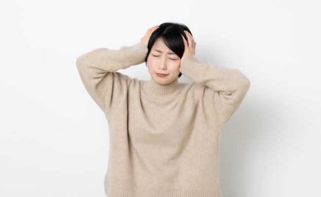頭を抱えて悩む女性のイメージ